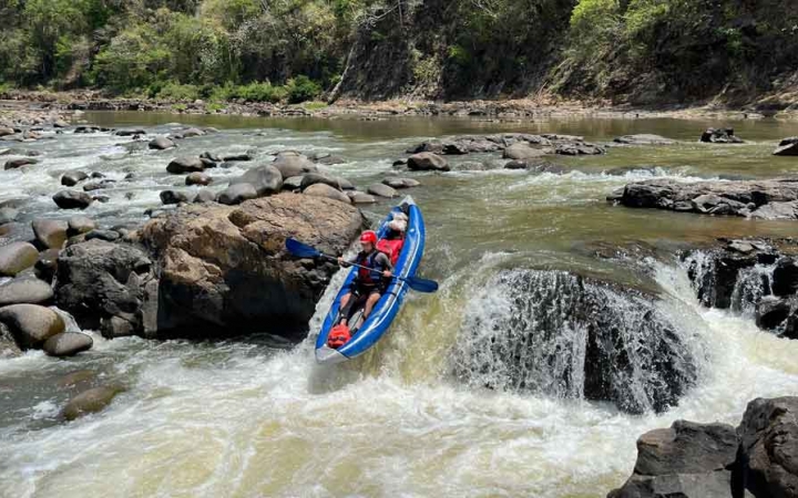 a person navigates a small waterfall in a watercraft on an outward bound expedition 